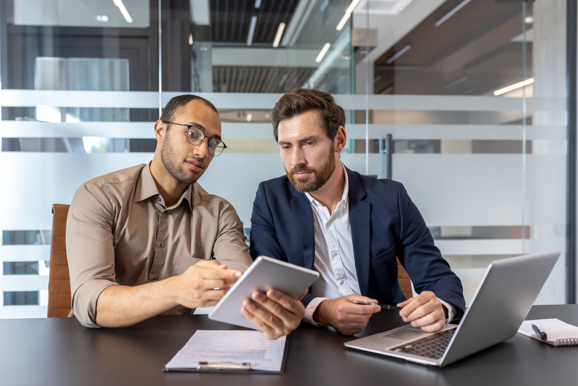 two men talking and looking at a notepad