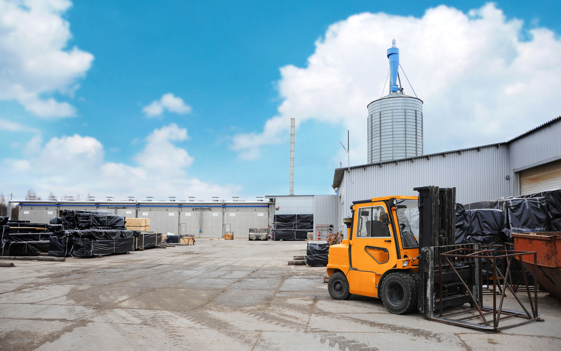 Lumber warehouse territory. Orange forklift at woodworking plant.