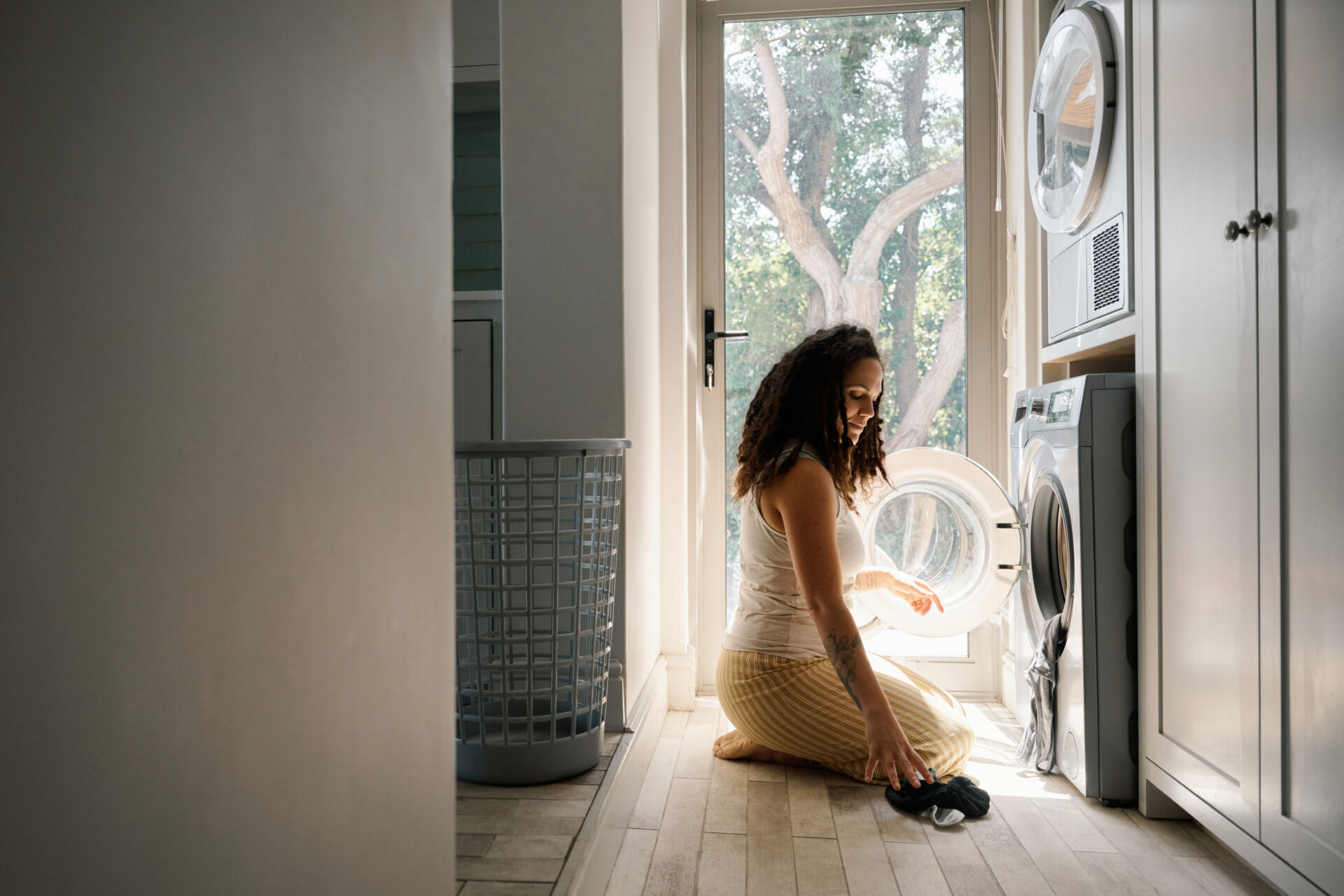 Woman crouching beside a washer and dryer in a laundry room