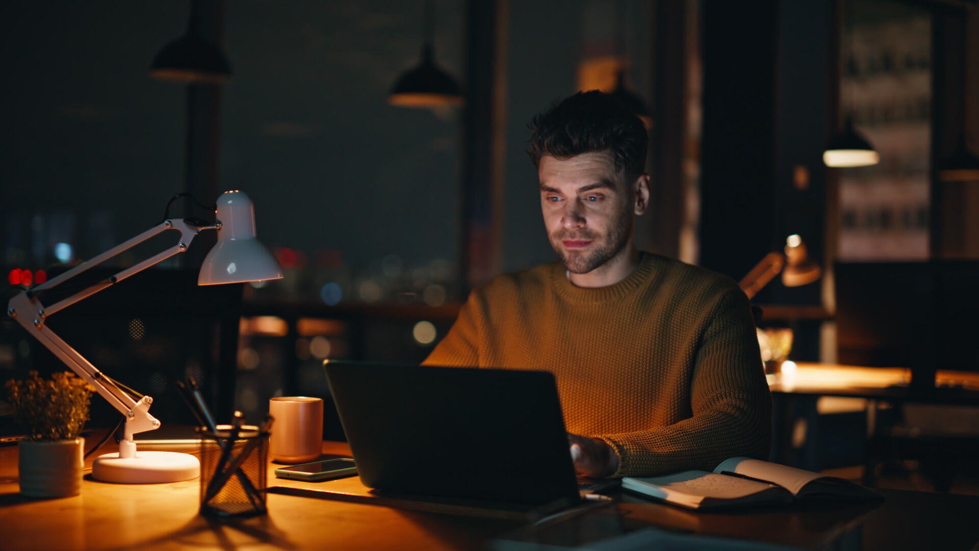 Successful manager working at night creative agency office closeup. Smiling businessman reading email at laptop thinking on business growth. Happy man freelancer satisfied online project late evening.