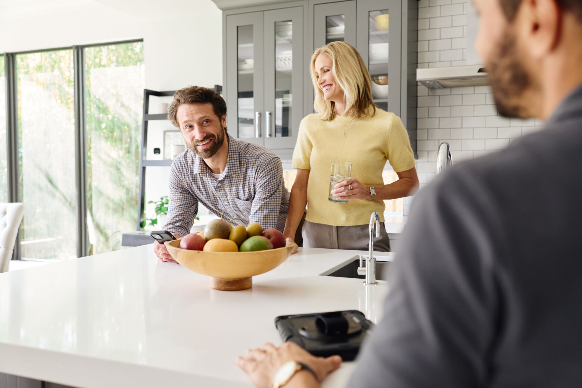 Three people standing by a kitchen counter talking