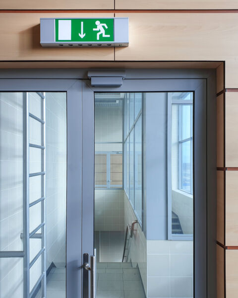 Emergency exit with glass door in airport office building. Emergency fire doors. Rescue signs icon green emergency exit lamp