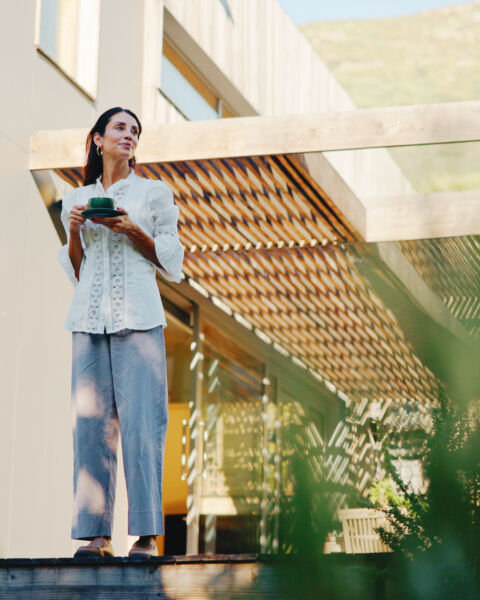 Woman holding a mug on an outdoor stairway beside a wooden deck