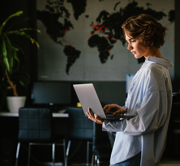 Employee standing with a laptop in an office, reviewing filtered security activity across locations