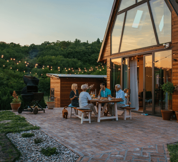 A-frame house at dusk with people gathered on the patio below