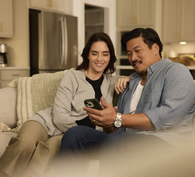 Two people looking at a phone together on a couch at home