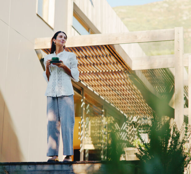 Woman holding a mug on an outdoor stairway beside a wooden deck