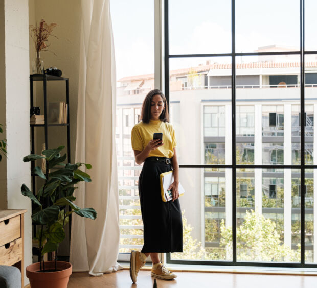 woman on her phone standing by a window