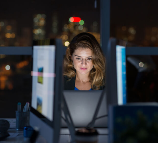 Analyst running a search across activity history on a monitor in a darkened office at night