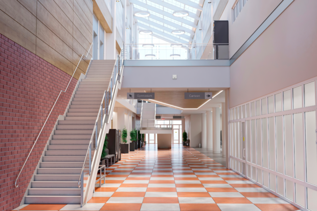 Bright school atrium with an open staircase and tiled corridor