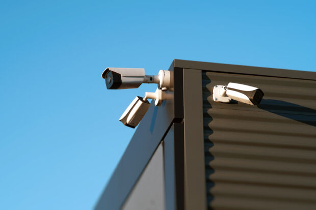 The image provides a closeup view of several security cameras that are installed on the exterior of a modern building